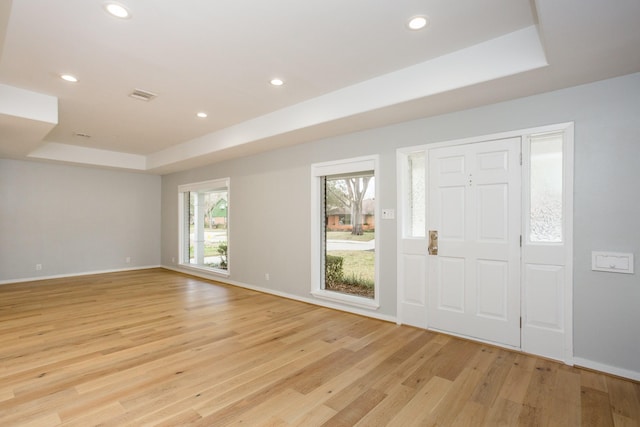 entryway featuring a raised ceiling and light wood-type flooring