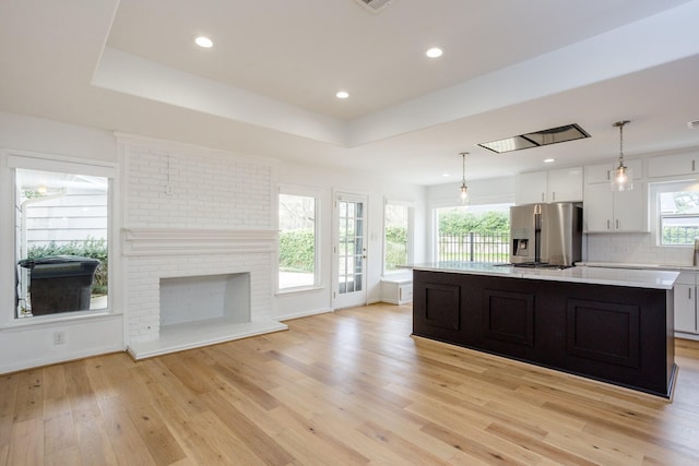 kitchen featuring white cabinetry, appliances with stainless steel finishes, a tray ceiling, and decorative light fixtures