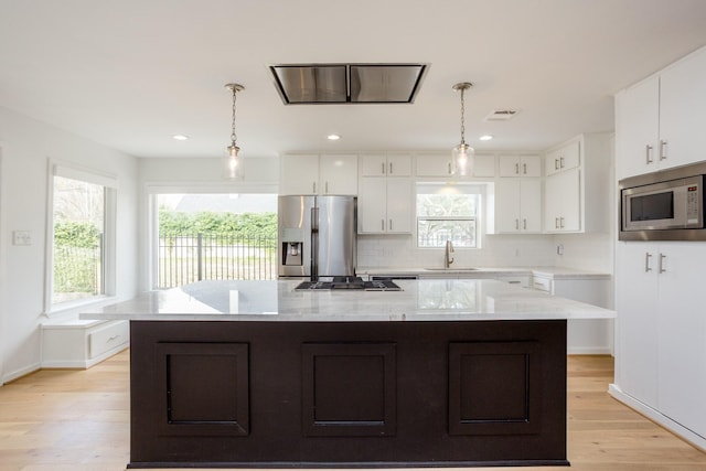 kitchen with a kitchen island, white cabinetry, appliances with stainless steel finishes, and sink