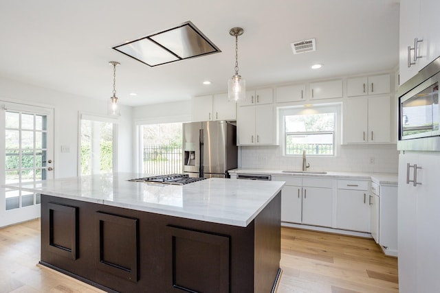 kitchen featuring white cabinetry, sink, stainless steel appliances, and a kitchen island