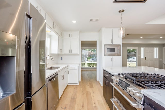 kitchen featuring white cabinetry, sink, pendant lighting, and appliances with stainless steel finishes