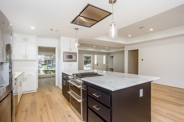 kitchen featuring built in microwave, white cabinetry, a kitchen island, and decorative light fixtures