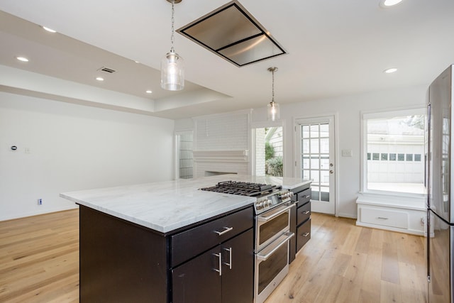 kitchen with a kitchen island, appliances with stainless steel finishes, light hardwood / wood-style floors, and decorative light fixtures