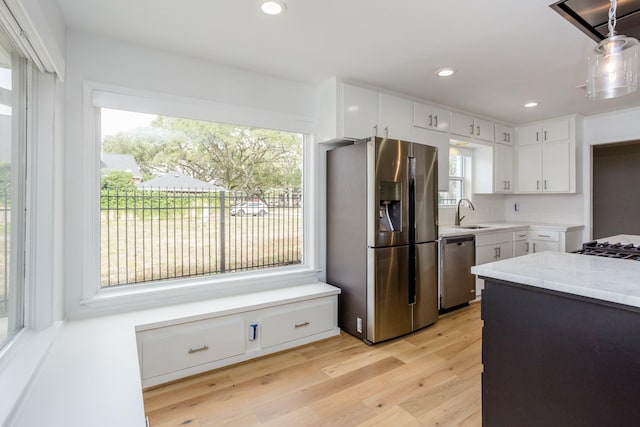 kitchen with sink, appliances with stainless steel finishes, white cabinetry, tasteful backsplash, and light hardwood / wood-style floors