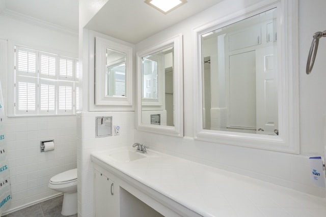 bathroom with tile patterned floors, toilet, tile walls, vanity, and ornamental molding