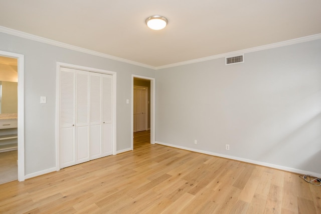 unfurnished bedroom featuring crown molding, light hardwood / wood-style floors, and a closet