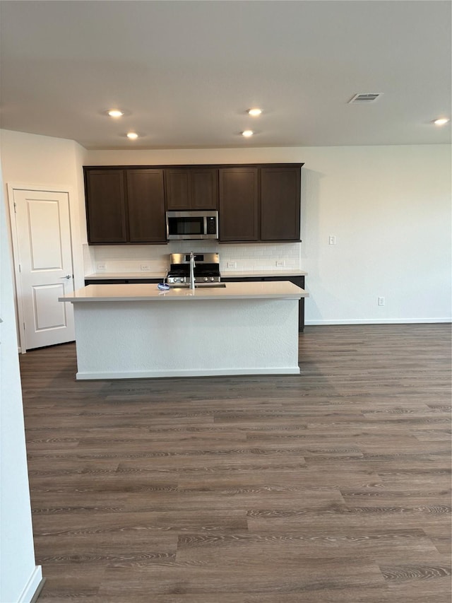 kitchen featuring stainless steel appliances, dark brown cabinets, sink, and a center island with sink