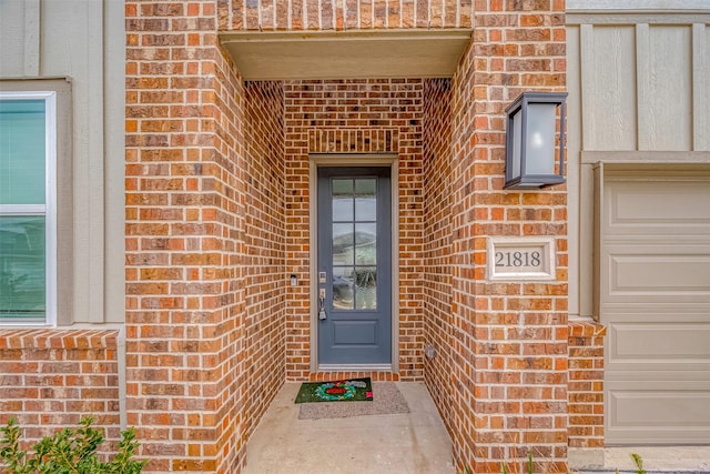 doorway to property with a garage and brick siding