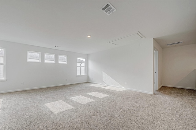 unfurnished room featuring attic access, light colored carpet, visible vents, and baseboards