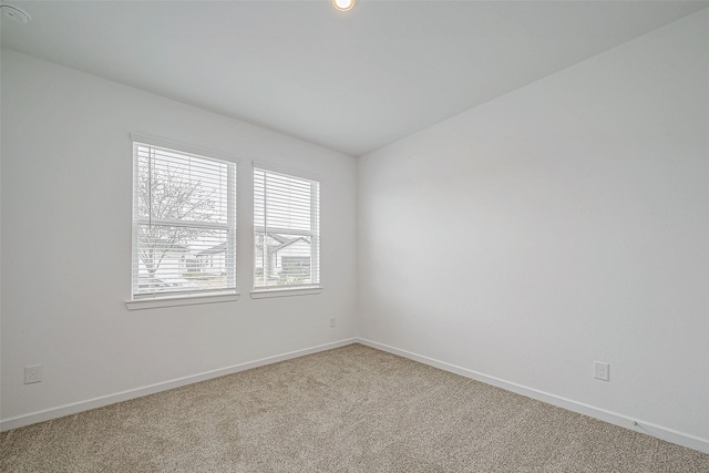 unfurnished room featuring light carpet and baseboards