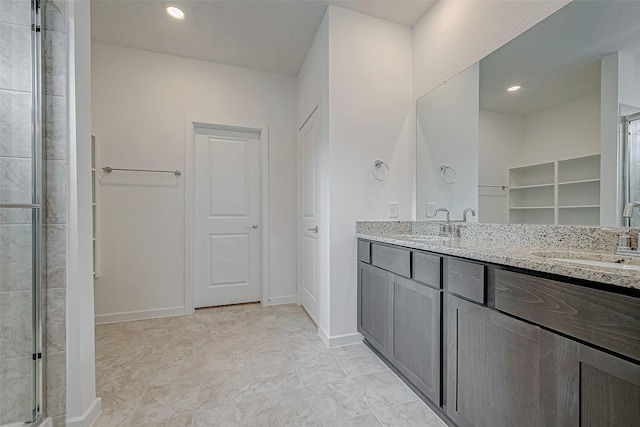 full bathroom with double vanity, recessed lighting, a sink, and baseboards