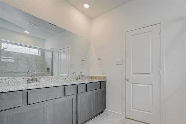 bathroom featuring baseboards, a sink, visible vents, and a shower stall