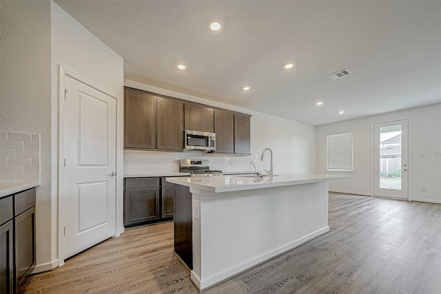 kitchen featuring a center island with sink, visible vents, stainless steel appliances, and light countertops