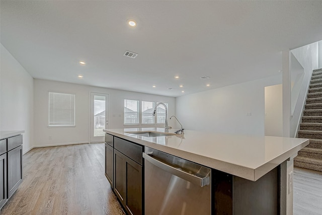 kitchen with light countertops, visible vents, stainless steel dishwasher, a sink, and an island with sink