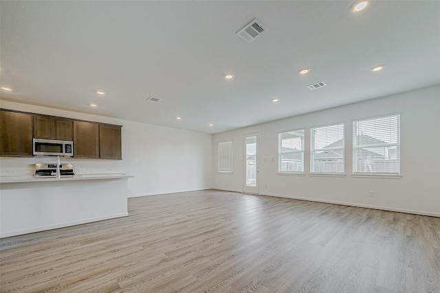 unfurnished living room featuring light wood-style floors, baseboards, visible vents, and recessed lighting