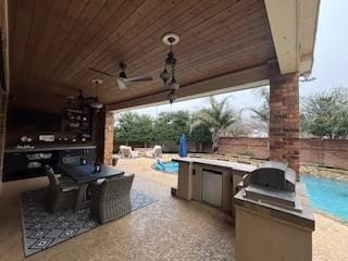 view of patio with a fenced in pool, ceiling fan, and an outdoor kitchen