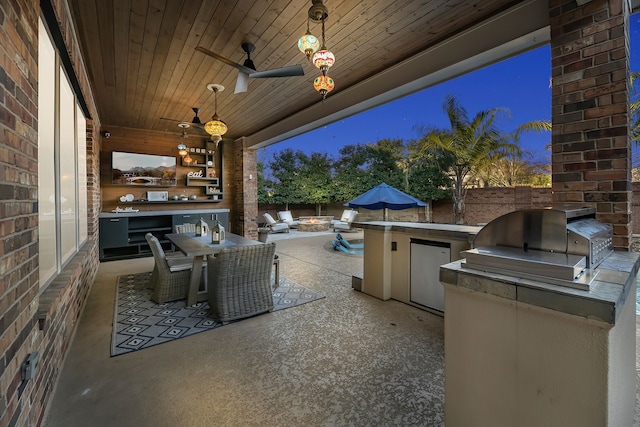 view of patio featuring a grill, fence, an outdoor kitchen, and a ceiling fan