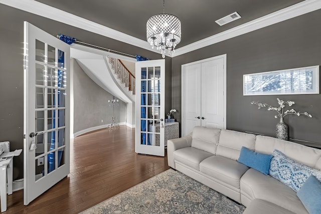 living room with french doors, visible vents, ornamental molding, wood finished floors, and a chandelier