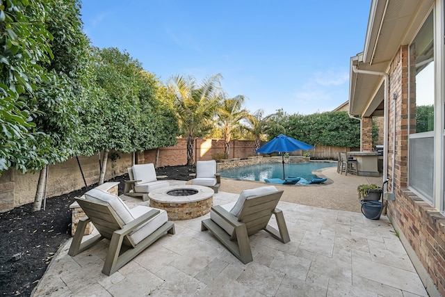 view of patio / terrace featuring a bar, an outdoor fire pit, a fenced backyard, and a fenced in pool