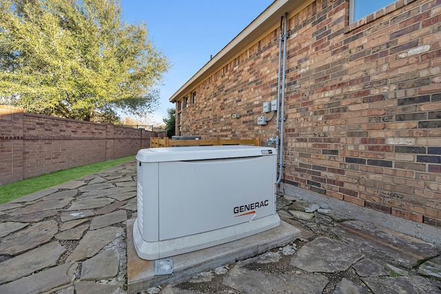 details featuring fence, a power unit, and brick siding