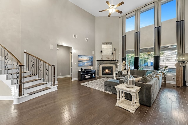 living room with plenty of natural light, a glass covered fireplace, and dark wood finished floors