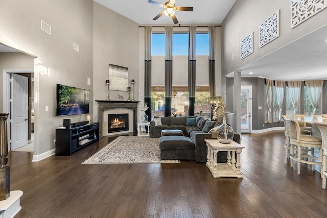 living area featuring dark wood-type flooring, visible vents, plenty of natural light, and a lit fireplace