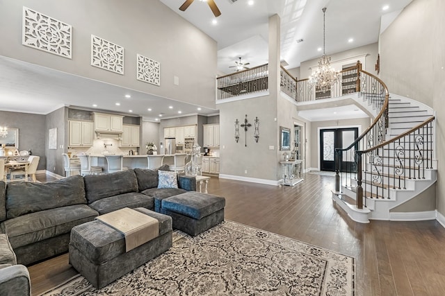 living room featuring stairs, ceiling fan with notable chandelier, wood finished floors, and baseboards