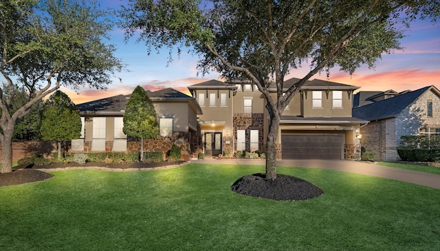 view of front facade with a garage, concrete driveway, stone siding, a yard, and stucco siding