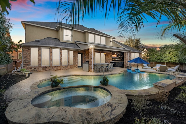 pool at dusk with a fenced in pool, a patio, outdoor dry bar, an in ground hot tub, and fence