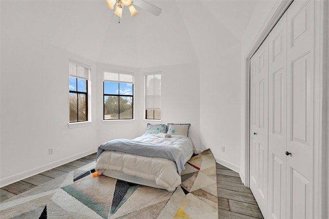 bedroom with wood-type flooring, ceiling fan, high vaulted ceiling, and a closet