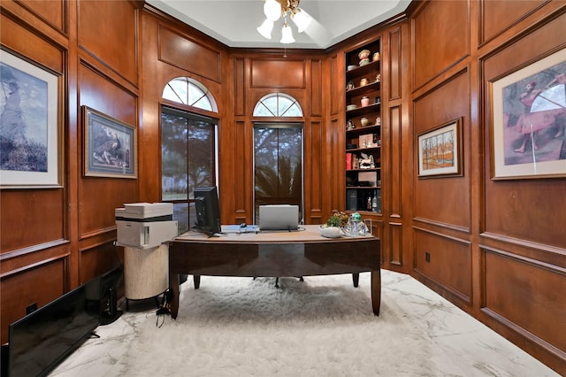 office with wood walls, ceiling fan, and built in shelves