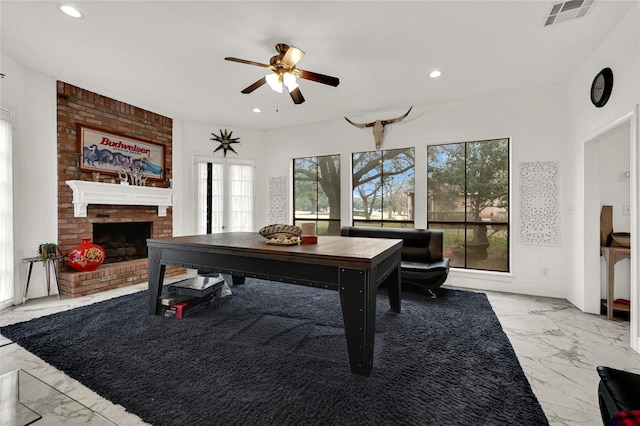 playroom with a brick fireplace and ceiling fan