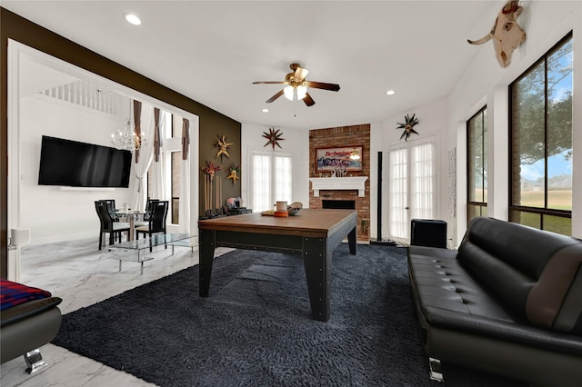 interior space with plenty of natural light, ceiling fan with notable chandelier, and a fireplace