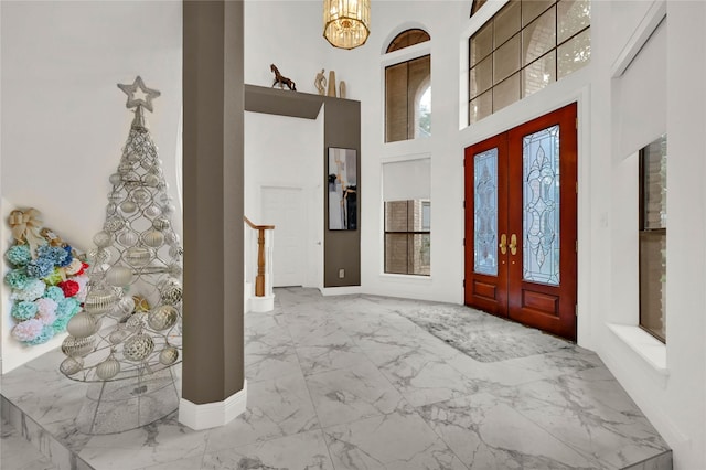 entrance foyer with french doors, a towering ceiling, and a notable chandelier