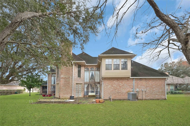 rear view of house with central AC unit and a yard