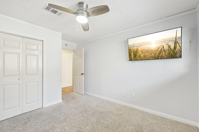 unfurnished bedroom featuring crown molding, ceiling fan, light carpet, and a closet