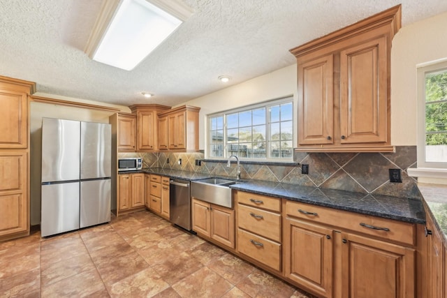 kitchen featuring tasteful backsplash, sink, stainless steel appliances, and a textured ceiling