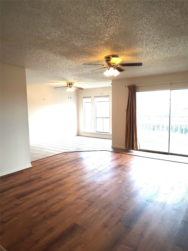 empty room featuring ceiling fan, dark wood-type flooring, and a textured ceiling