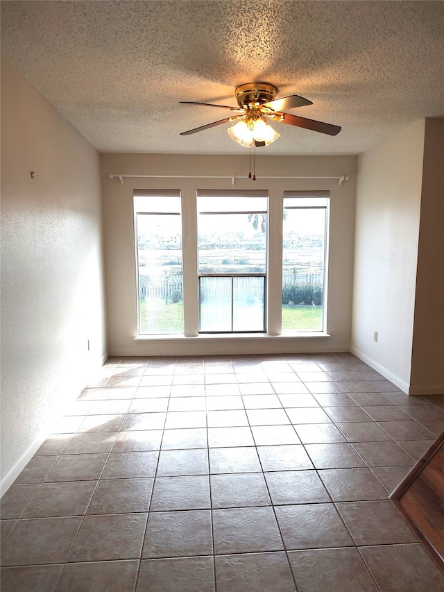 tiled empty room featuring ceiling fan and a textured ceiling