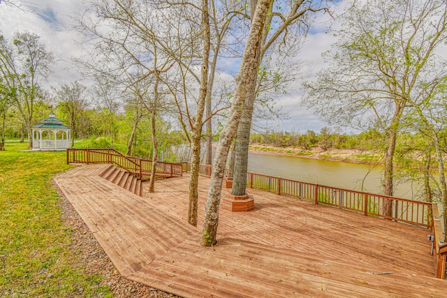 wooden terrace featuring a gazebo, a water view, and a lawn