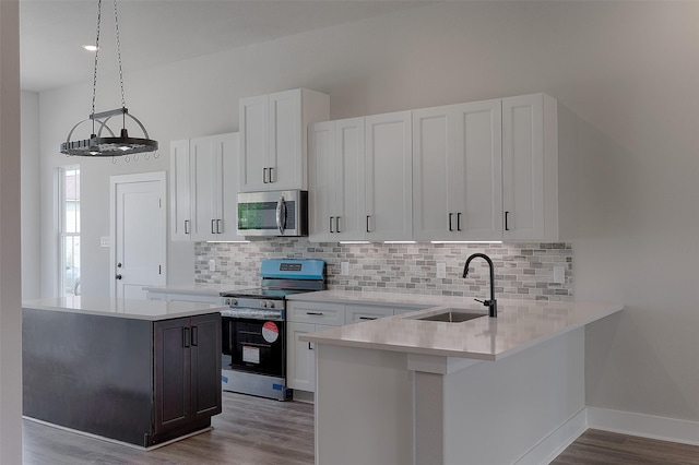 kitchen with appliances with stainless steel finishes, white cabinetry, light countertops, and a sink