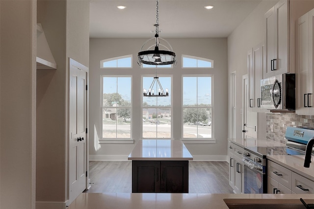 kitchen featuring stainless steel appliances, white cabinets, decorative backsplash, and light wood finished floors