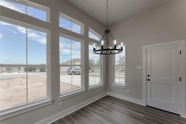 unfurnished dining area with dark wood-style floors, a notable chandelier, plenty of natural light, and baseboards