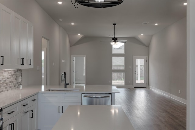 kitchen featuring a peninsula, a sink, light countertops, dishwasher, and backsplash