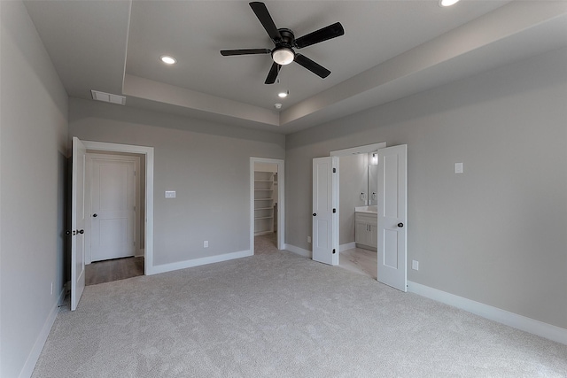 unfurnished bedroom with visible vents, baseboards, recessed lighting, a walk in closet, and light colored carpet