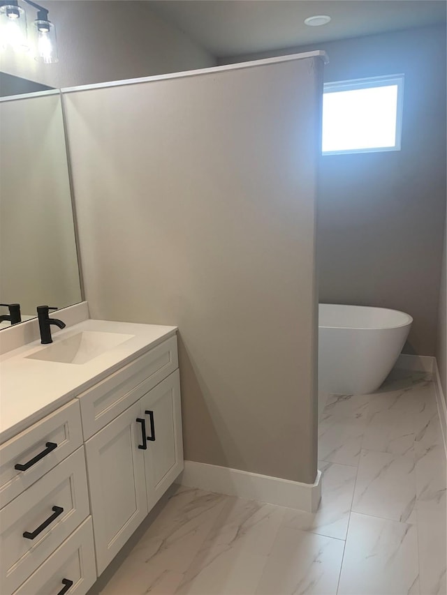 bathroom featuring vanity, a freestanding tub, baseboards, and marble finish floor