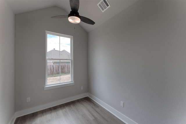 spare room featuring light wood-type flooring, visible vents, baseboards, lofted ceiling, and ceiling fan