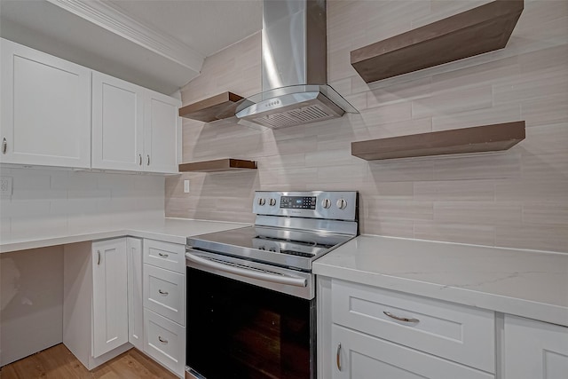 kitchen with decorative backsplash, white cabinetry, electric range, and wall chimney exhaust hood