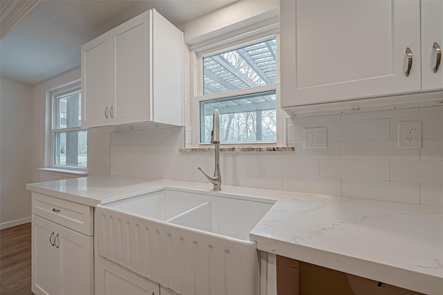 kitchen featuring dark wood-type flooring, sink, white cabinetry, light stone counters, and backsplash