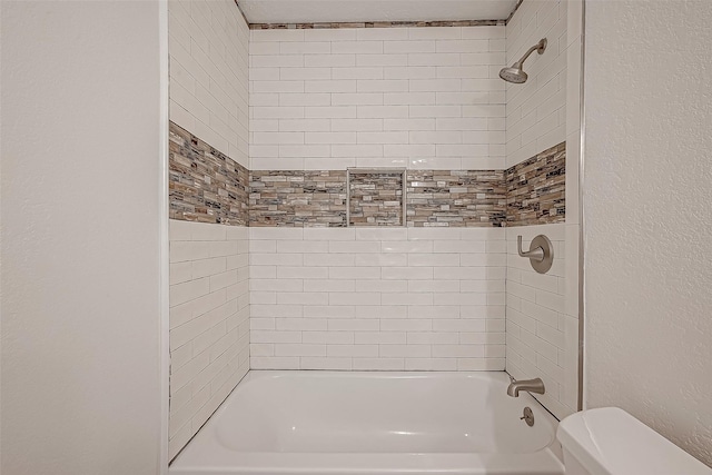 bathroom with tiled shower / bath combo and toilet